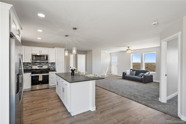 kitchen with a center island, wood-type flooring, white cabinetry, stainless steel appliances, and ceiling fan