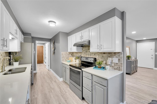 7902 Meade St Unit A10, Westminster, CO 80030 - kitchen featuring electric range, under cabinet range hood, a sink, backsplash, and gray cabinets