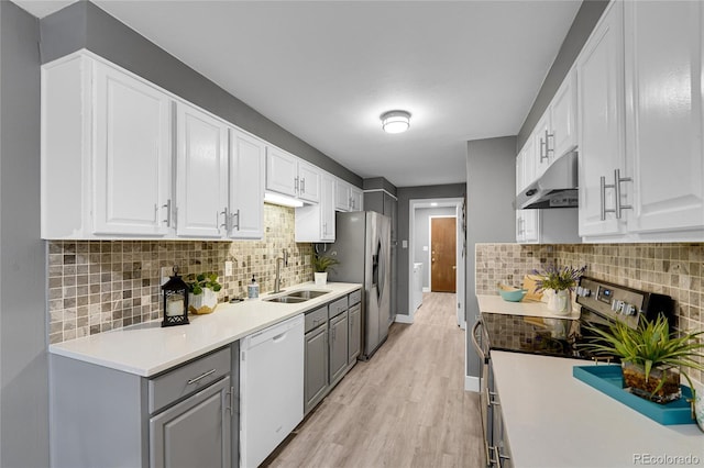 7902 Meade St Unit A10, Westminster, CO 80030 - kitchen with under cabinet range hood, appliances with stainless steel finishes, a sink, gray cabinets, and light wood-style flooring