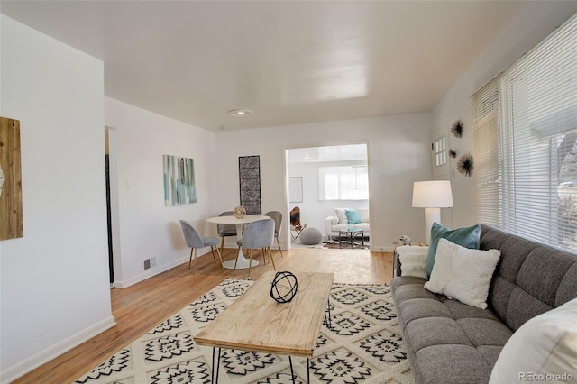 living room featuring baseboards, visible vents, and light wood-style floors