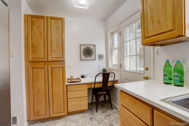 interior space with built in desk, a sink, visible vents, and baseboards