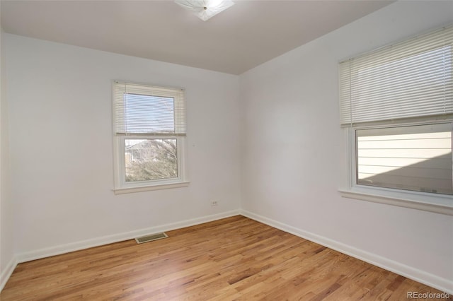 spare room with visible vents, light wood-style flooring, and baseboards