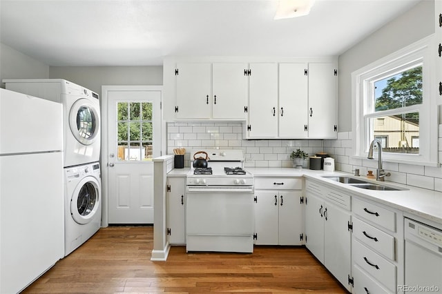 2000 S King St, Denver, CO 80219 - kitchen featuring white appliances, stacked washer / dryer, backsplash, light countertops, and white cabinetry