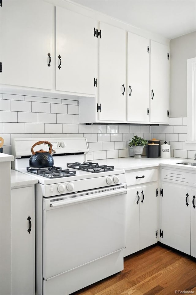 2000 S King St, Denver, CO 80219 - kitchen featuring white gas range oven, white cabinetry, tasteful backsplash, and light countertops