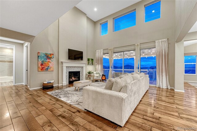 2775 Morningbird Ln, Castle Rock, CO 80109 - living room featuring wood-type flooring, baseboards, a tiled fireplace, and a high ceiling