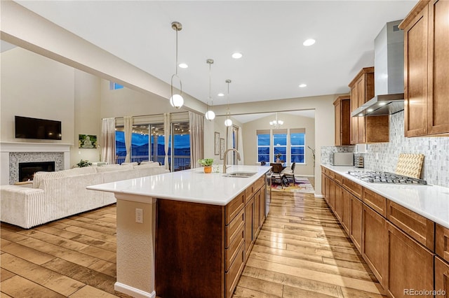 2775 Morningbird Ln, Castle Rock, CO 80109 - kitchen featuring light wood-style flooring, a sink, wall chimney range hood, stainless steel gas cooktop, and light countertops