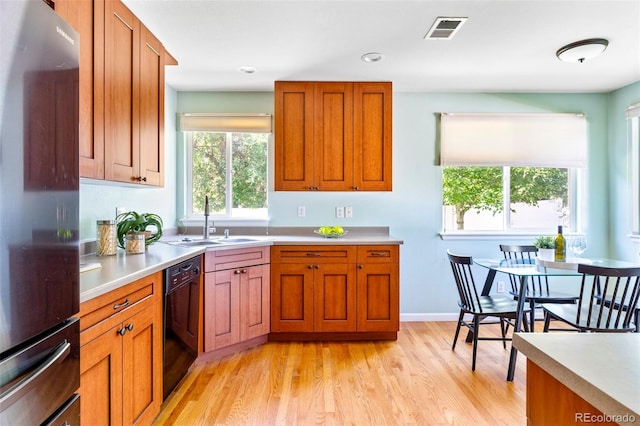 9168 W 50th Ln Unit 1, Arvada, CO 80002 - kitchen featuring refrigerator, dishwasher, light countertops, light wood-type flooring, and brown cabinets