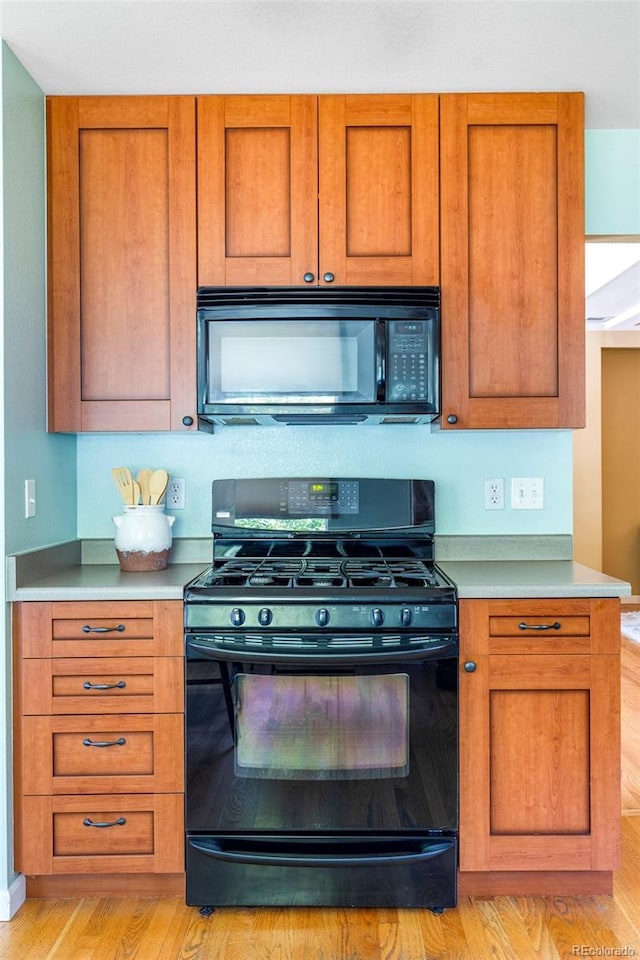 9168 W 50th Ln Unit 1, Arvada, CO 80002 - kitchen featuring black appliances, brown cabinetry, light wood-type flooring, and light countertops