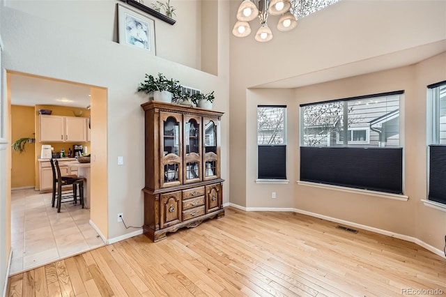 5163 Apache Creek Rd, Castle Rock, CO 80109 - spare room featuring light wood-style floors, baseboards, a chandelier, and a towering ceiling