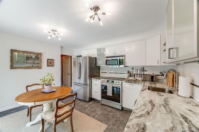 1565 Sagrimore Cir, Lafayette, CO 80026 - kitchen featuring stainless steel appliances, a chandelier, decorative backsplash, white cabinetry, and light stone countertops