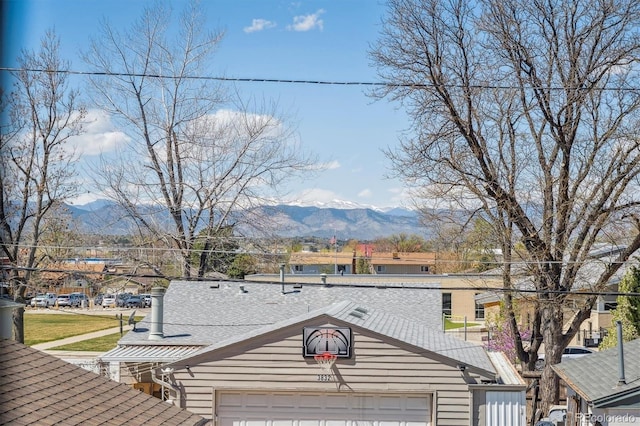 exterior space with an attached garage, roof with shingles, and a mountain view