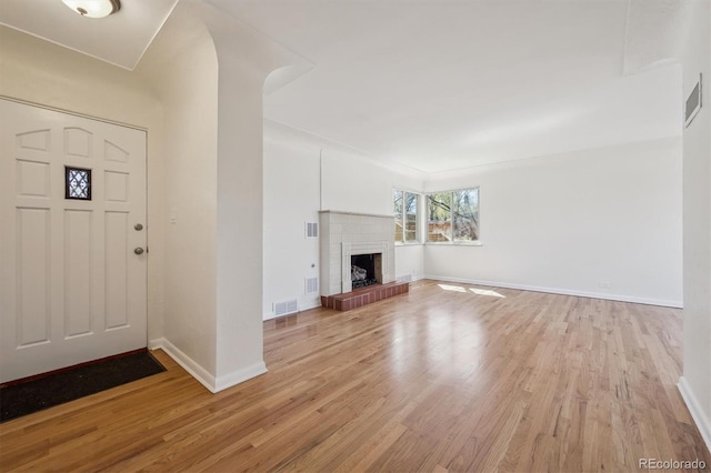 entrance foyer with a fireplace, light wood-type flooring, visible vents, and baseboards