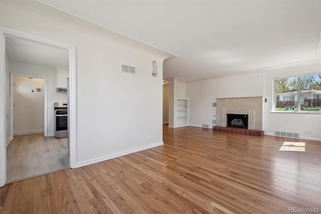unfurnished living room featuring baseboards, light wood finished floors, and visible vents