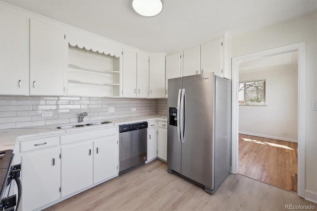 kitchen featuring open shelves, a sink, decorative backsplash, light wood-style floors, and appliances with stainless steel finishes