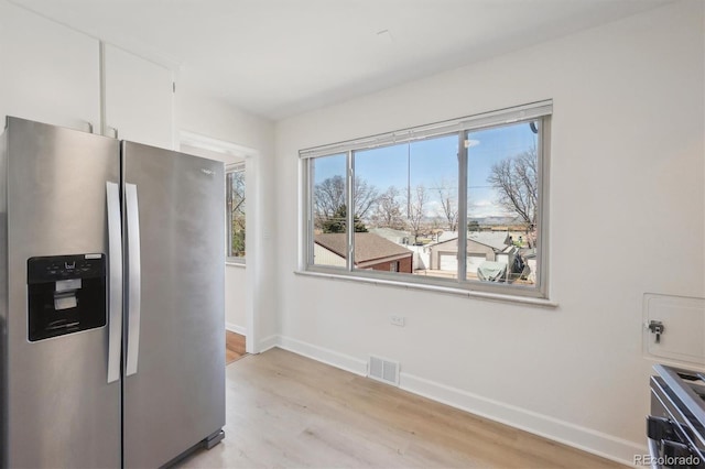 kitchen featuring visible vents, baseboards, light wood-style flooring, stainless steel refrigerator with ice dispenser, and white cabinetry