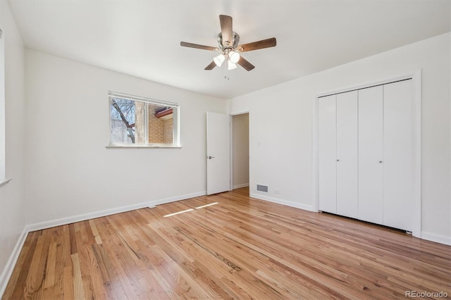 unfurnished bedroom featuring light wood finished floors, baseboards, and a closet