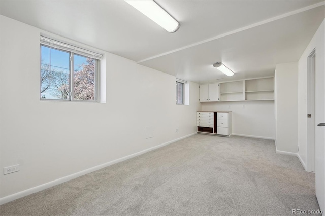 basement featuring light colored carpet and baseboards
