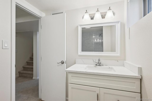 bathroom with visible vents, vanity, and a shower