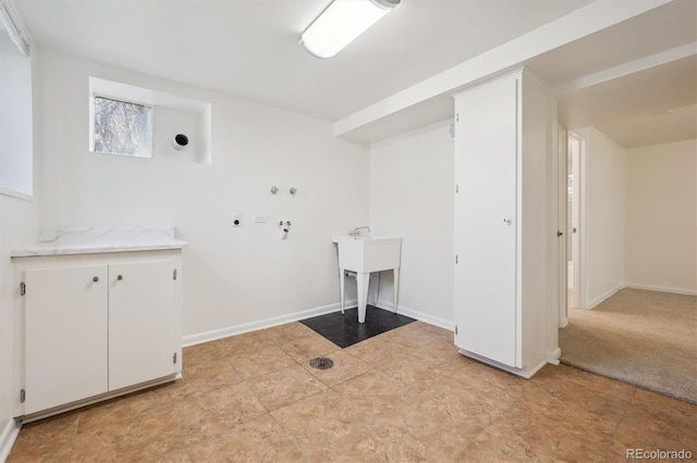 clothes washing area with light tile patterned flooring, baseboards, and a sink