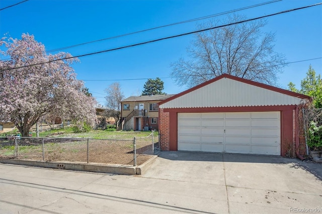 view of front of home featuring brick siding, a detached garage, an outbuilding, and fence