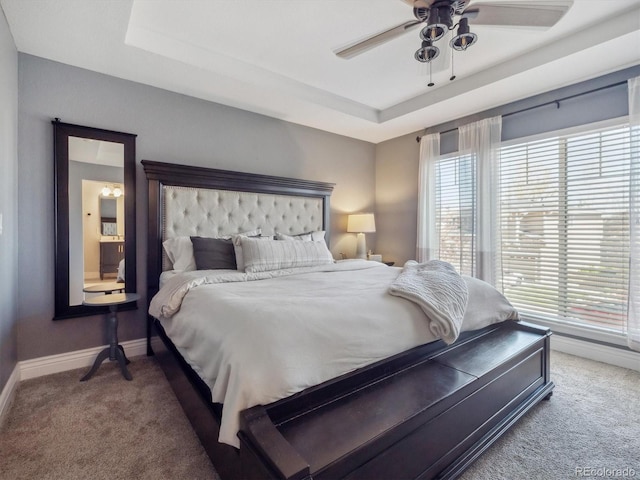 carpeted bedroom featuring a raised ceiling, baseboards, and ceiling fan