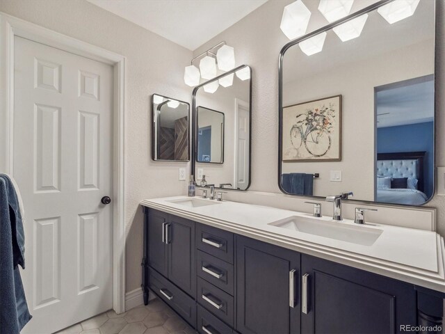 ensuite bathroom featuring double vanity and tile patterned flooring