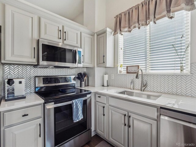 kitchen featuring appliances with stainless steel finishes, a sink, backsplash, light countertops, and white cabinetry