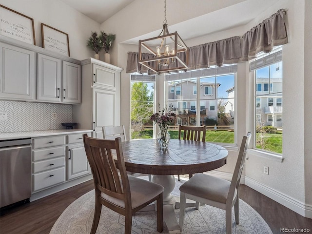dining room with dark wood finished floors, healthy amount of natural light, baseboards, and a chandelier
