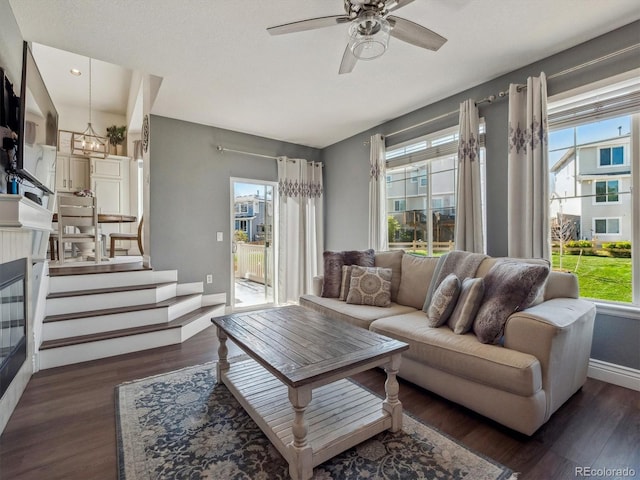 living room with wood finished floors, ceiling fan, baseboards, and a chandelier