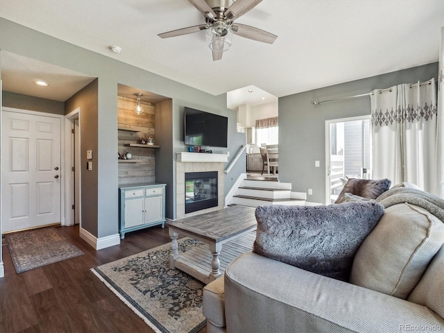 living room with baseboards, wood finished floors, a ceiling fan, a tile fireplace, and recessed lighting