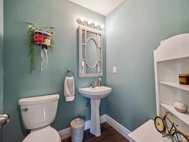 bathroom featuring wood finished floors, toilet, and a sink