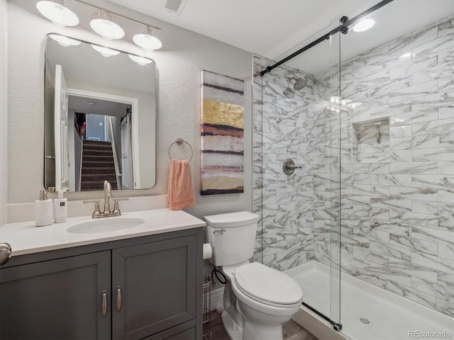 full bathroom with a stall shower, vanity, toilet, and a textured wall