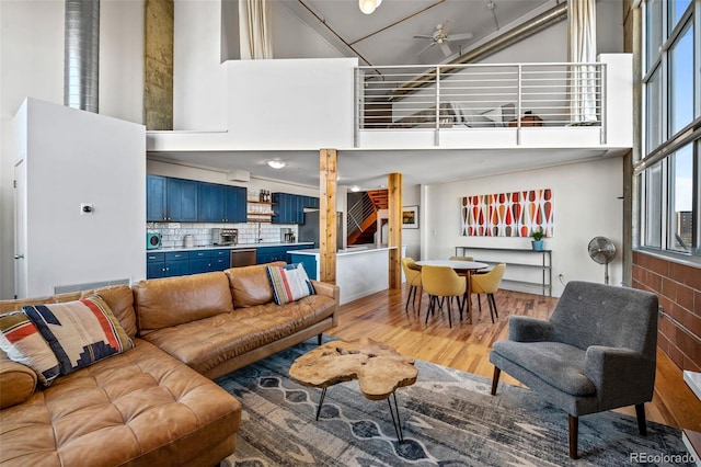 living room featuring wood-type flooring, a high ceiling, and ceiling fan