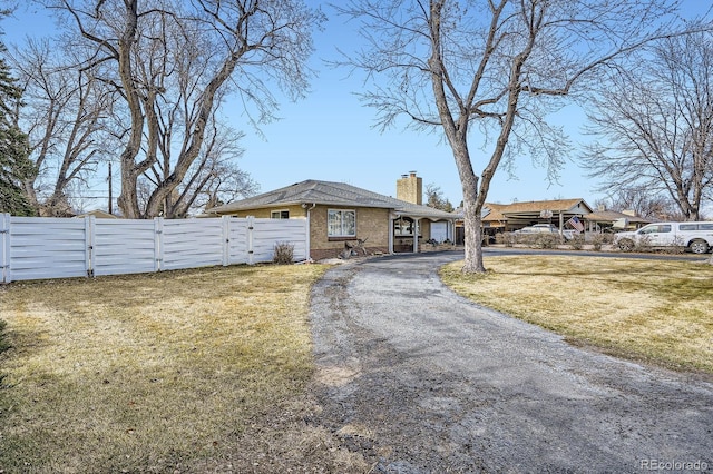 view of front of home with driveway, a gate, fence, brick siding, and a chimney