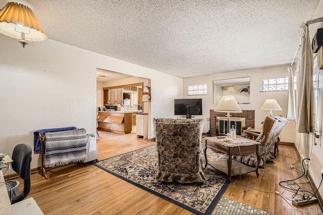 living area with light wood-style flooring, a textured ceiling, and baseboards