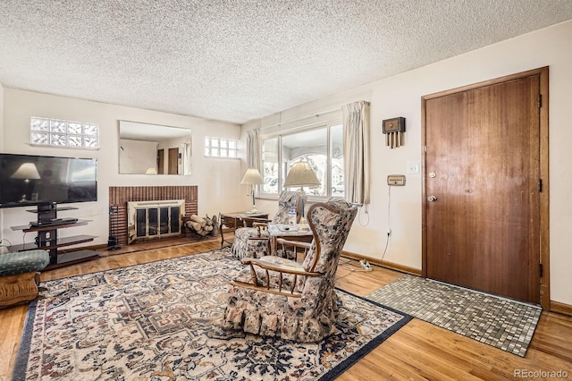 living area featuring a textured ceiling, a brick fireplace, and wood finished floors