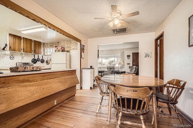 dining area with ceiling fan, light wood-style floors, visible vents, and a textured ceiling