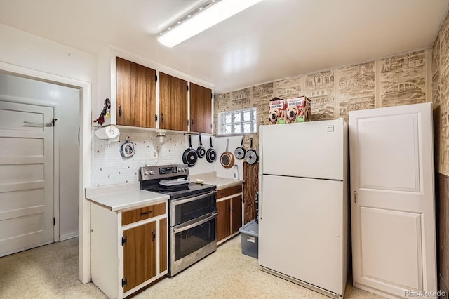 kitchen with backsplash, double oven range, light countertops, brown cabinets, and freestanding refrigerator