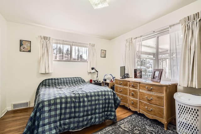 bedroom with visible vents, baseboards, and wood finished floors