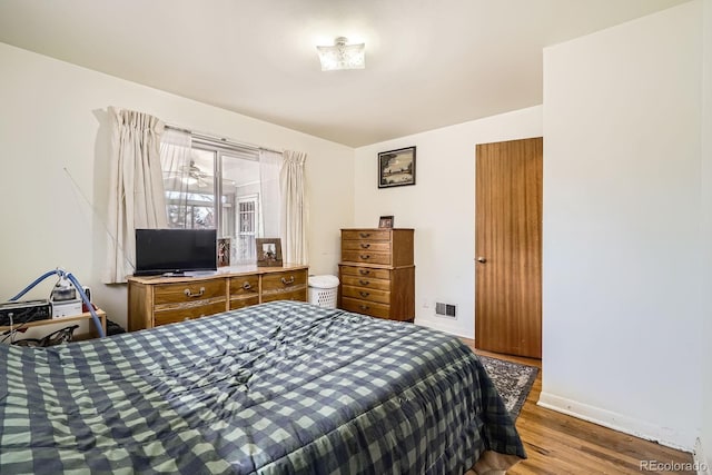 bedroom featuring wood finished floors, visible vents, and baseboards