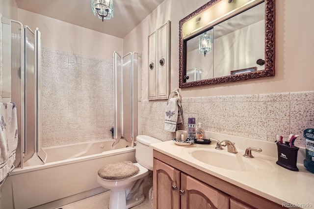 bathroom with toilet, tile walls, wainscoting, bathtub / shower combination, and vanity