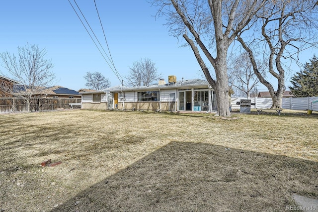 rear view of house featuring fence, a lawn, and a chimney