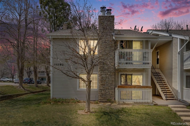back of property with a shingled roof, stairs, and a chimney
