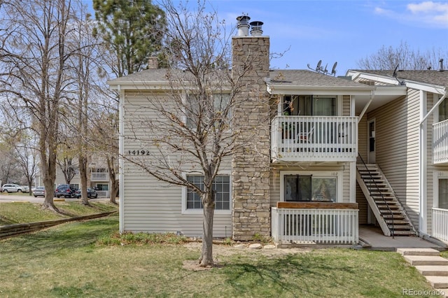 back of property with a shingled roof, a chimney, a yard, and stairway