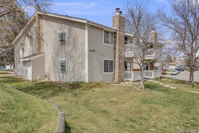 view of home's exterior with a lawn, a chimney, and a balcony