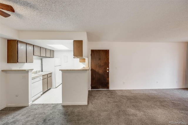 kitchen with light countertops, a textured ceiling, light carpet, and white appliances