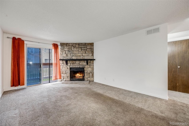 unfurnished living room with a stone fireplace, carpet flooring, a textured ceiling, and visible vents