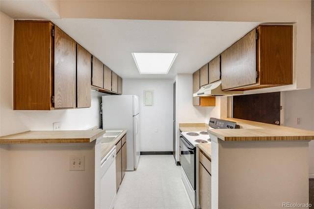 kitchen with a peninsula, white appliances, baseboards, light floors, and light countertops