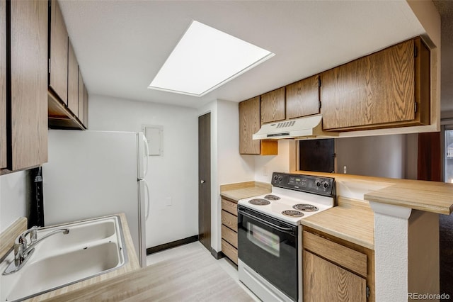 kitchen featuring a sink, freestanding refrigerator, under cabinet range hood, a skylight, and range with electric stovetop
