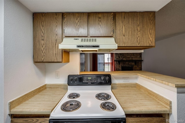 kitchen with under cabinet range hood, range with electric cooktop, a stone fireplace, and light countertops